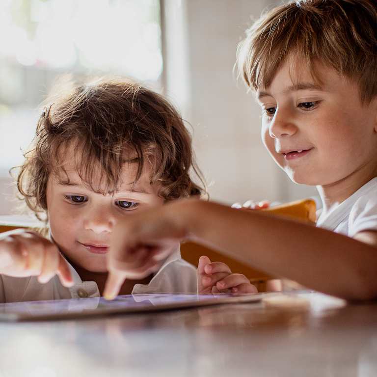 Zwei kleine Kinder, spielen auf einem Tablet.